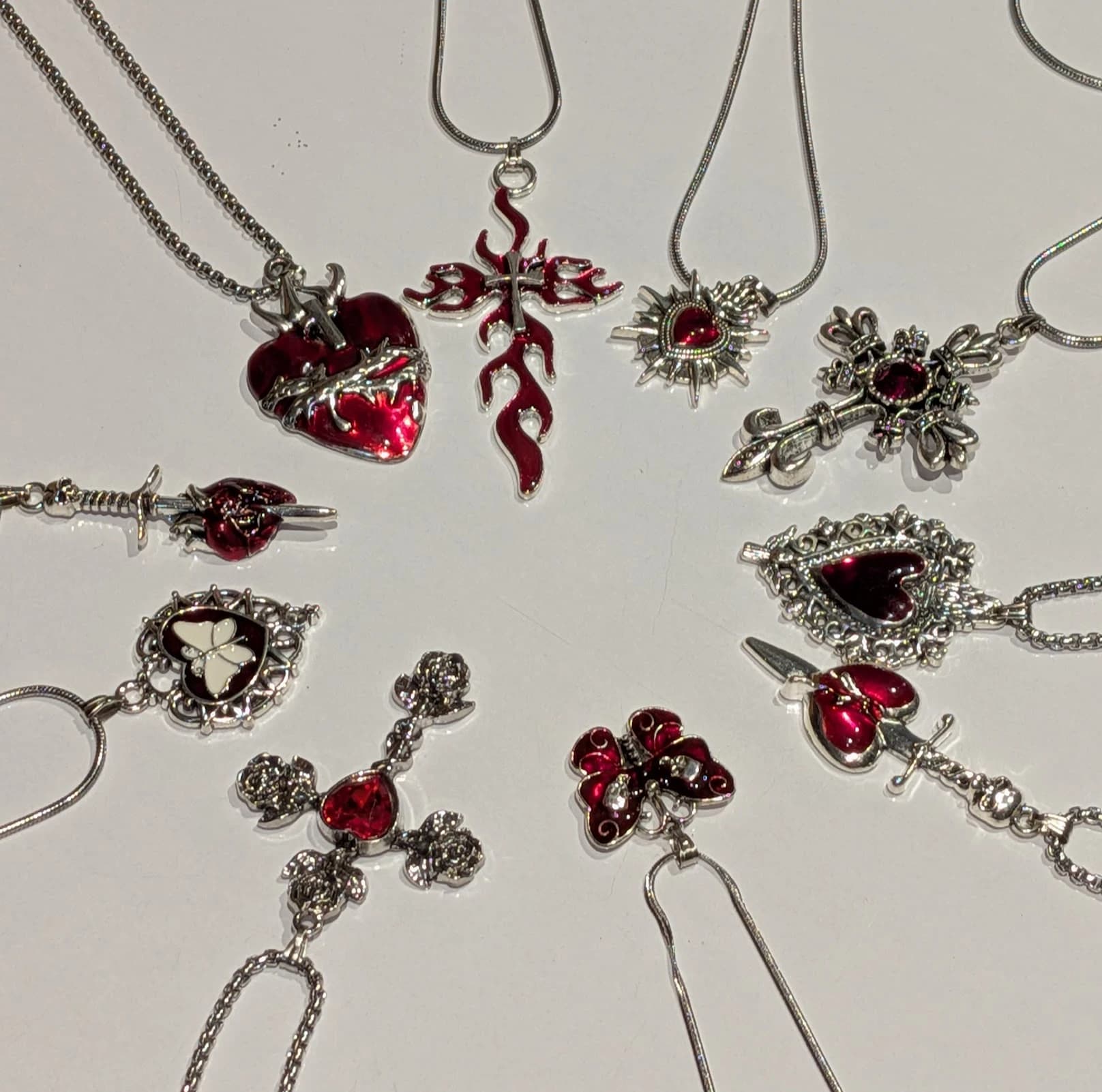 A circle of red enamel pendants — hearts, crosses and a butterfly — laid on bone